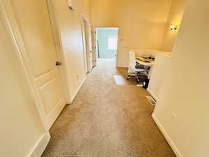 Hallway featuring a desk and light carpet