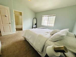 Bedroom with vaulted ceiling, carpet, and ensuite bath