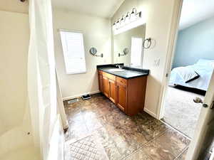 Ensuite bathroom with vanity, dark carpet, a shower with curtain, and vaulted ceiling