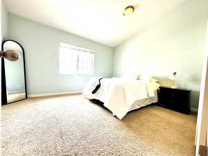 Bedroom with light carpet and vaulted ceiling