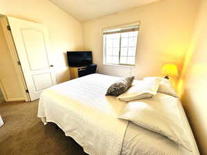 Bedroom with lofted ceiling and carpet