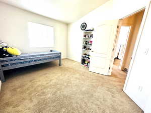 Carpeted bedroom with lofted ceiling and baseboards