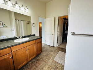 Full bath with vanity, a spacious closet, and a shower with curtain