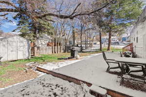 Fenced backyard featuring a storage unit, a residential view, and outdoor dining space