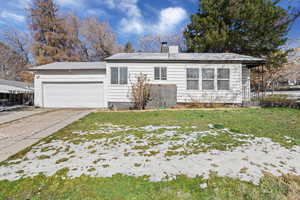 View of front of property featuring a chimney, an attached garage, a front lawn, and concrete driveway