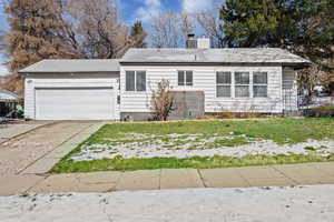 Ranch-style house featuring an attached garage, driveway, a front yard, and a chimney
