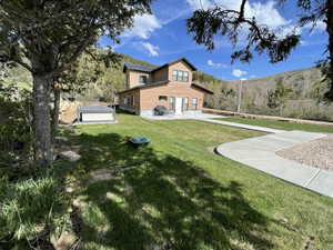Back of house with a lawn, a patio, and a mountain view