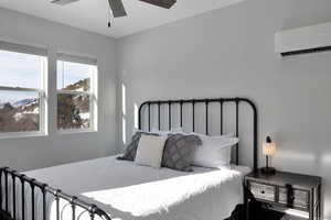 Bedroom with a wall mounted mini split and a ceiling fan