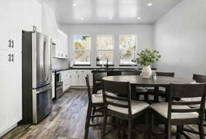 Kitchen featuring stainless steel appliances, dark countertops, recessed lighting, white cabinetry, and dark wood-type flooring
