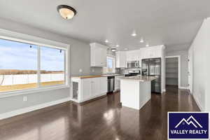 Kitchen featuring white cabinets, stainless steel appliances, a center island, dark wood-type flooring, and recessed lighting