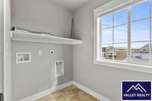 Laundry area with hookup for a washing machine, electric dryer hookup, and stone finish floors