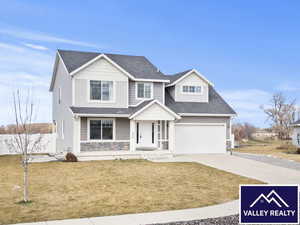 View of front of property featuring concrete driveway, a front yard, a shingled roof, stone siding, and covered porch