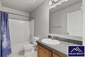 Full bath featuring vanity, shower / bath combo with shower curtain, and light tile patterned floors