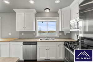 Kitchen with stainless steel appliances, white cabinetry, recessed lighting, and light countertops