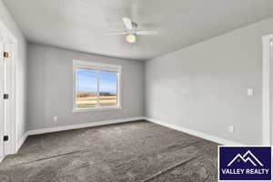 Carpeted empty room featuring a ceiling fan and a textured ceiling