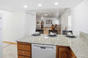 Kitchen featuring a peninsula, white appliances, wood finish cabinetry, light stone countertops, and recessed lighting