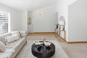 Carpeted living area featuring vaulted ceiling and suspended lighting