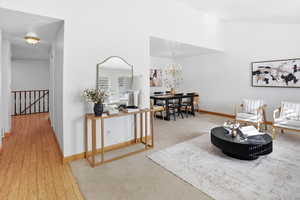 Living area with hanging lights, light colored carpet, and a high ceiling