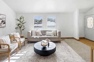 Carpeted living room with vaulted ceiling and baseboards