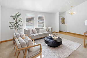 Carpeted living room featuring lofted ceiling and suspended lighting