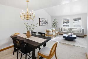 Dining area with vaulted ceiling, light carpet, and suspended lighting