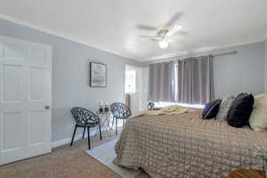 Carpeted bedroom with ornamental molding and a ceiling fan