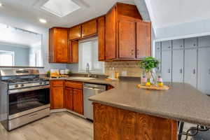 Kitchen featuring a peninsula, stainless steel appliances, crown molding, a breakfast bar, and light wood-style floors