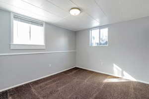 Spare room featuring dark colored carpet and baseboards