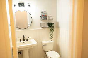 Half bath with toilet and a wainscoted wall.
