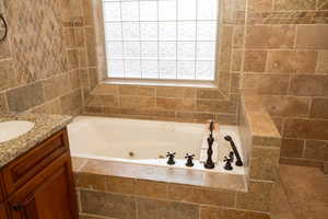 Full bathroom featuring a garden tub and vanity.