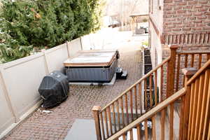 Fenced backyard with a patio area, grilling area, and a hot tub.