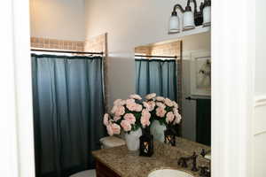 Bathroom with curtained shower and granite vanity.