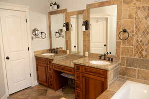 Master bathroom  with double granite vanity, a garden tub, and light tile flooring