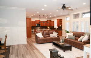 Open living area with LVP and radiant floor, ceiling fan, recessed lighting, ornamental molding.