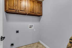 Laundry area with hookup for an electric dryer, cabinet space, and washer hookup
