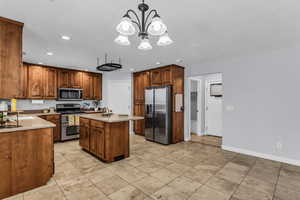 Kitchen with stainless steel appliances, a center island with sink, wood finish cabinetry, light Travertine patterned floors.