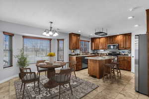 Kitchen with stainless steel appliances, wood finish cabinets, a kitchen island with sink, and island