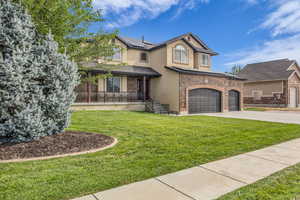 View of front of property featuring stucco siding, roof mounted solar panels, concrete driveway, and a front lawn