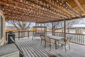 Wooden terrace featuring outdoor dining area, a grill, a fenced backyard, and a shed