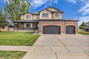 View of front facade featuring a front yard, roof mounted solar panels, covered porch, driveway, and stucco siding
