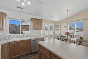 Kitchen with wood finish cabinetry, stainless steel dishwasher, light countertops, ceiling fan, and vaulted ceiling