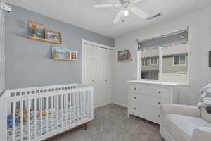 Bedroom with light colored carpet, a closet, a ceiling fan