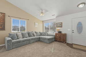 Carpeted living room featuring vaulted ceiling and a ceiling fan