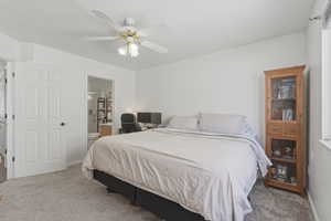 Bedroom with carpet floors, ensuite bath, and ceiling fan