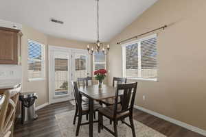 Dining room featuring lofted ceiling, dark wood-style floors, and a chandelier