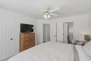Carpeted bedroom featuring ensuite bath and ceiling fan