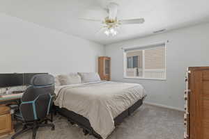 Carpeted bedroom with a desk and a ceiling fan