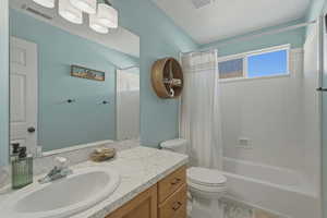 Full bathroom with vanity, shower / bath combination with curtain, and a textured ceiling