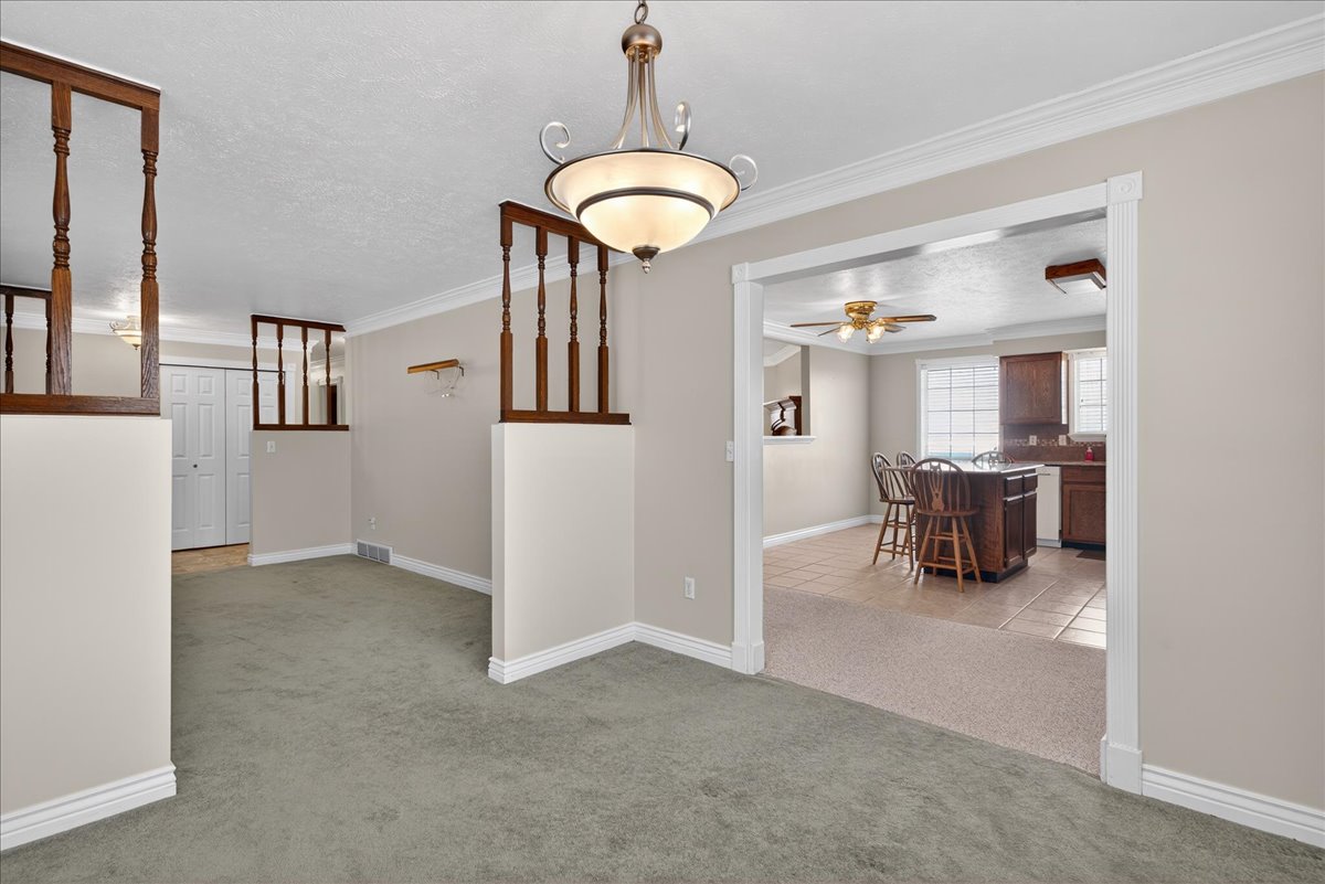 Corridor with light colored carpet, crown molding, a textured ceiling, and light tile patterned flooring