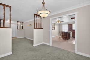 Corridor with light colored carpet, crown molding, a textured ceiling, and light tile patterned flooring